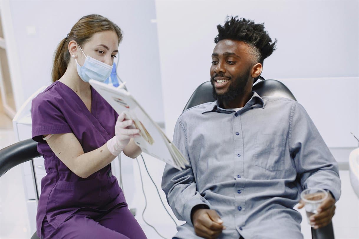 A dental professional showing a patient a record in the dental chair